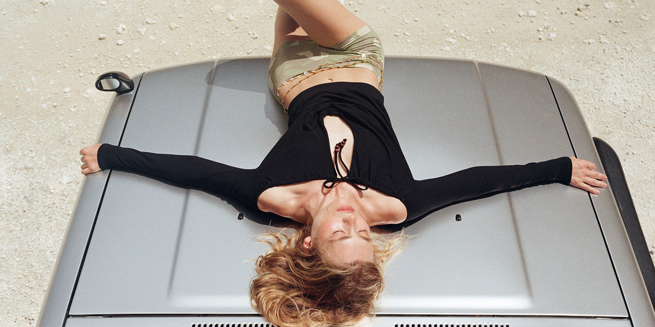 Person lying on a gray car with a neutral background